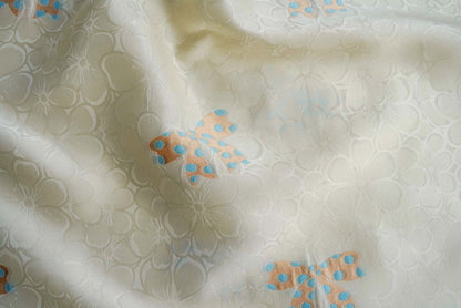 Tissu satin jacquard ivoire : motif nœud papillon, soyeux et lisse (165 cm de large)