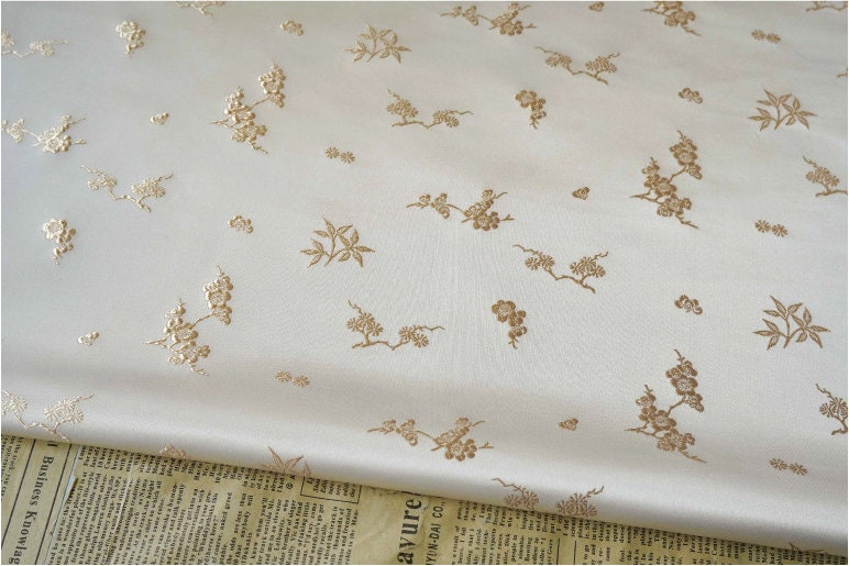 Tissu jacquard satiné ivoire : motif fleurs de prunier en relief, tissé, 165 cm de large