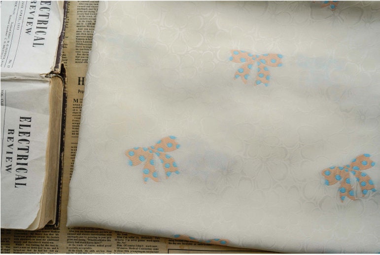 Tissu satin jacquard ivoire : motif nœud papillon, soyeux et lisse (165 cm de large)