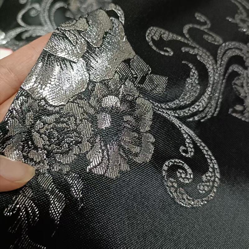 Tissu brocart jacquard noir : motif floral blanc nacré en relief, 150 cm de large