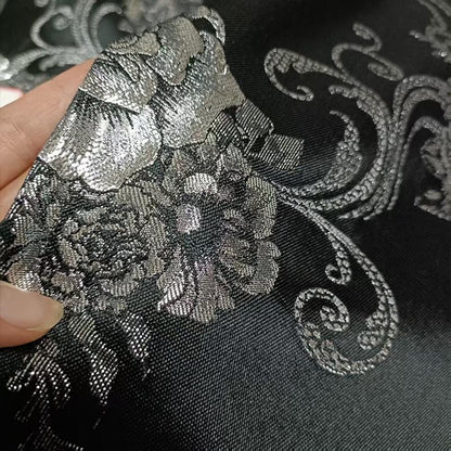 Tissu brocart jacquard noir : motif floral blanc nacré en relief, 150 cm de large