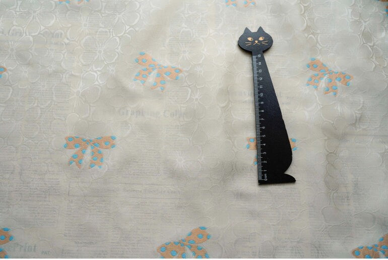 Tissu satin jacquard ivoire : motif nœud papillon, soyeux et lisse (165 cm de large)