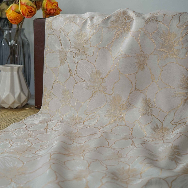 Tissu jacquard à broderie florale dorée : 162,5 cm de large. Idéal pour l’ameublement, les costumes et les rideaux. Vendu au mètre.