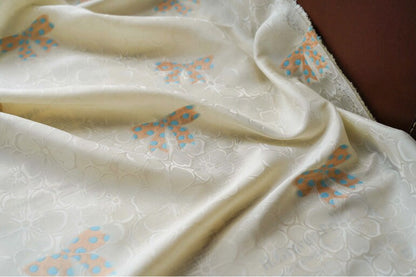 Tissu satin jacquard ivoire : motif nœud papillon, soyeux et lisse (165 cm de large)