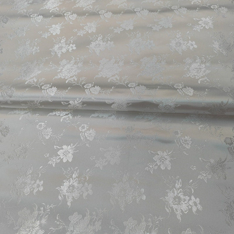 Tissu brocart floral métallisé blanc : rayonne de 114 cm de large, vendu au mètre